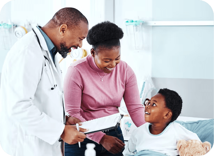 Médecin souriant échangeant avec une mère et son jeune fils installé dans un lit d’hôpital